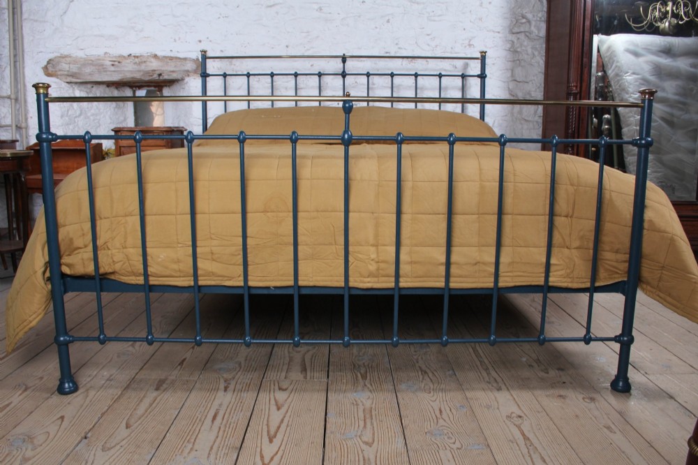 An Edwardian super king bedstead featuring a dark blue cast iron frame with vertical spindles and polished brass top rails. View III