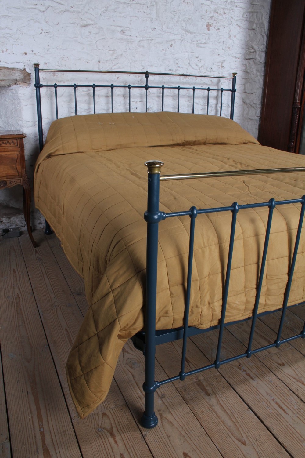 An Edwardian super king bedstead featuring a dark blue cast iron frame with vertical spindles and polished brass top rails. View VII