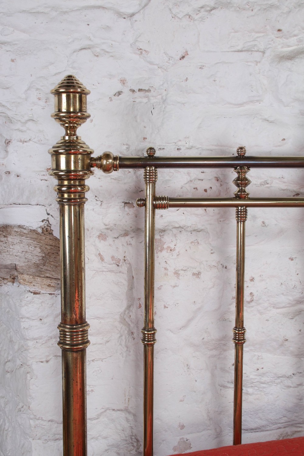An ornate Victorian polished brass super king bedstead featuring turned posts, decorative circular motifs, vertical spindles, and castors. View IX