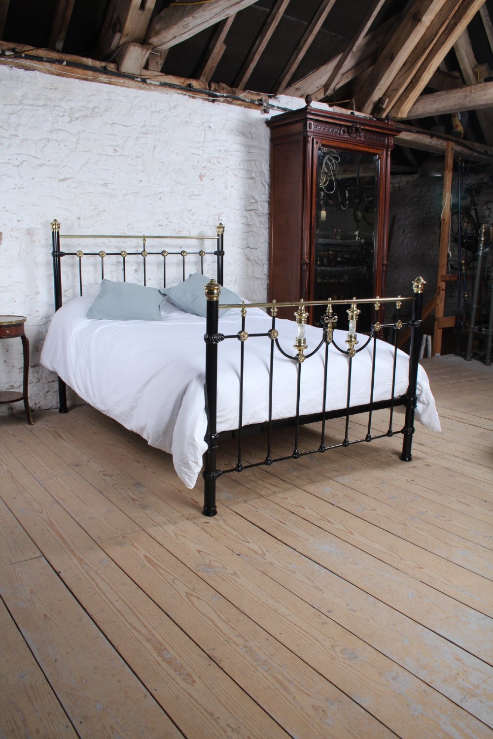 A Victorian black cast iron double bed frame with brass top rails, brass finials, and mother-of-pearl inlay details. View X