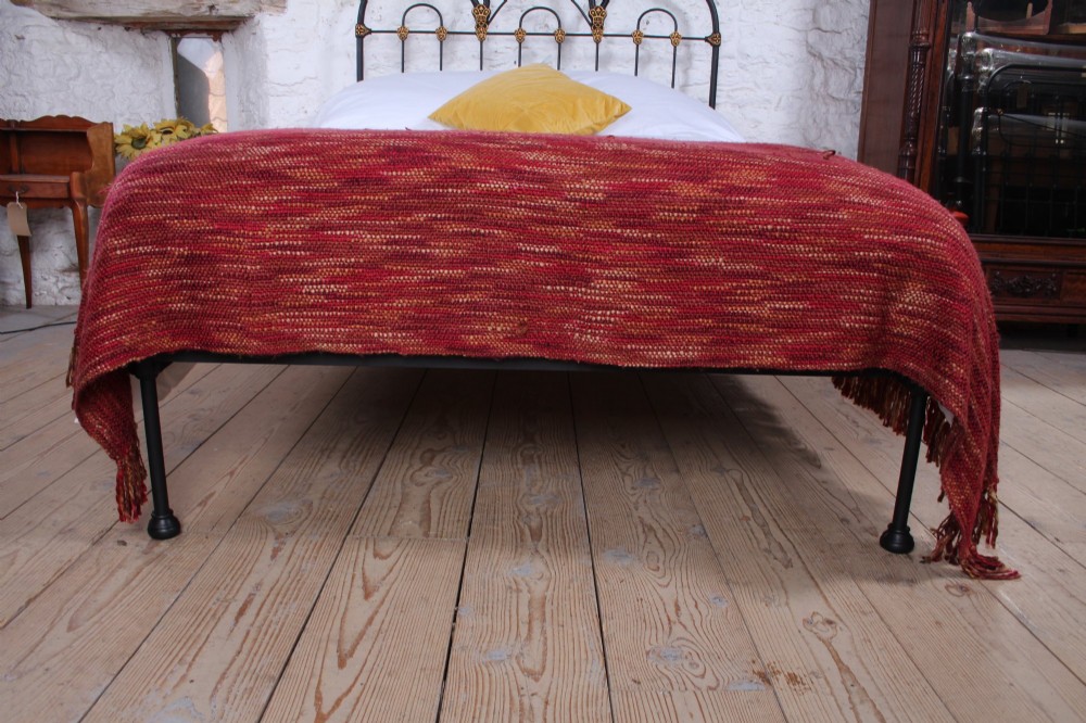 A black Victorian cast iron double bedstead featuring triple arched headboard metalwork with brass castings and a low foot end. View VI