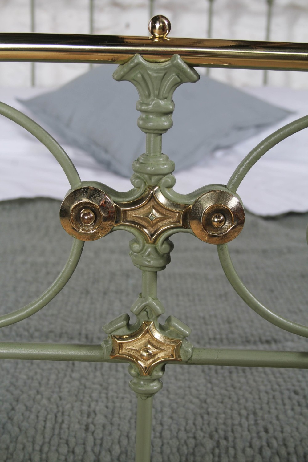 A Victorian sage green painted iron double bedstead featuring decorative scrollwork and polished brass top rails with spherical finials. View III