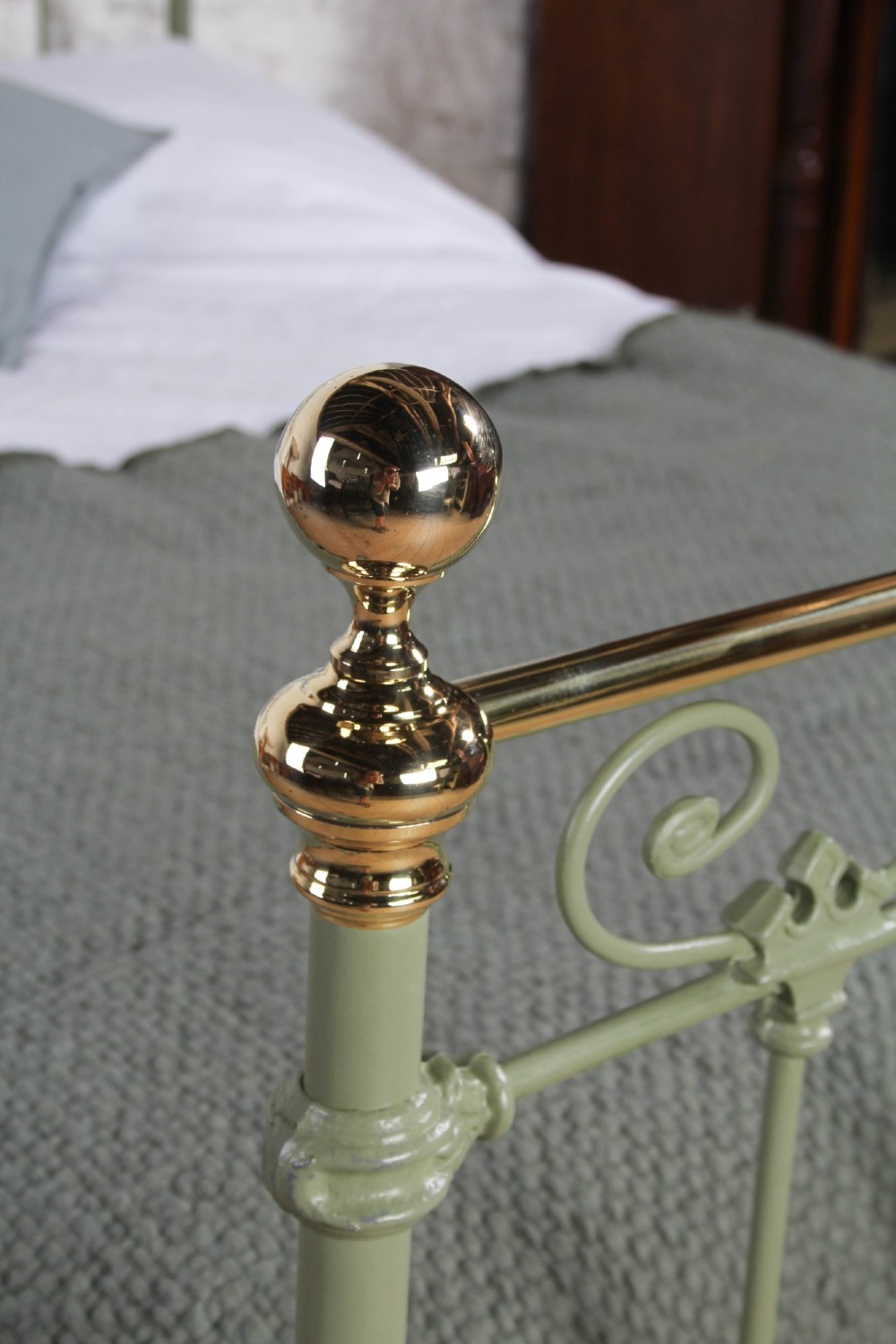 A Victorian sage green painted iron double bedstead featuring decorative scrollwork and polished brass top rails with spherical finials. View IV