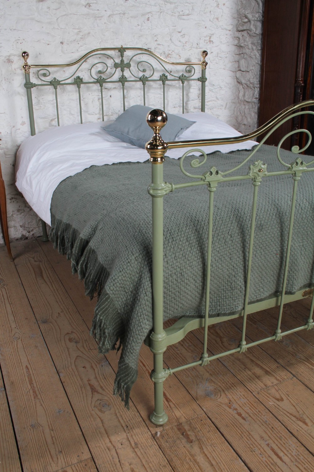 A Victorian sage green painted iron double bedstead featuring decorative scrollwork and polished brass top rails with spherical finials. View V