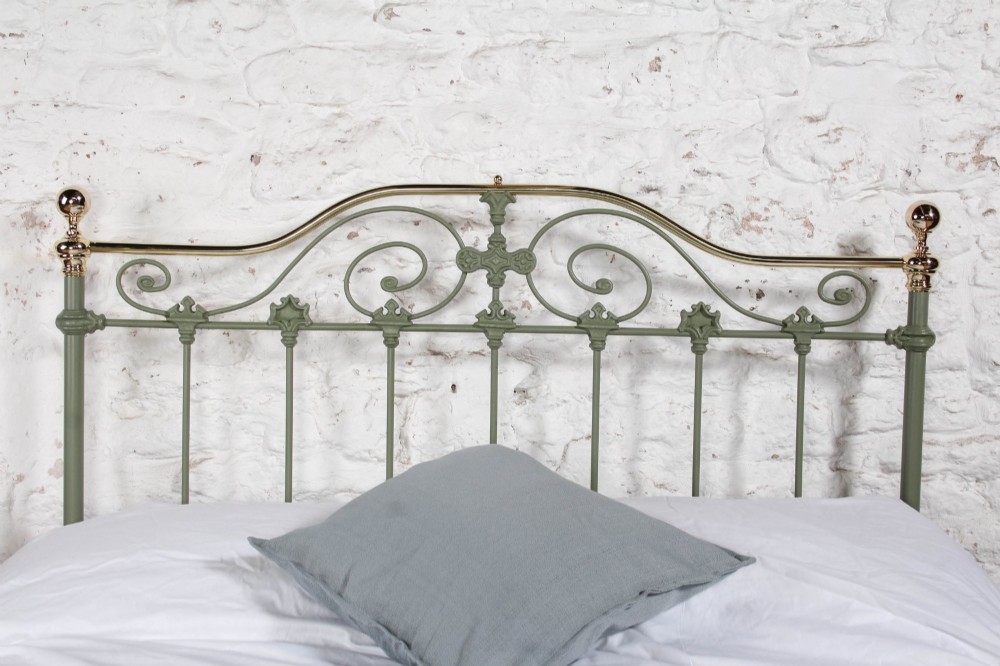 A Victorian sage green painted iron double bedstead featuring decorative scrollwork and polished brass top rails with spherical finials. View VI