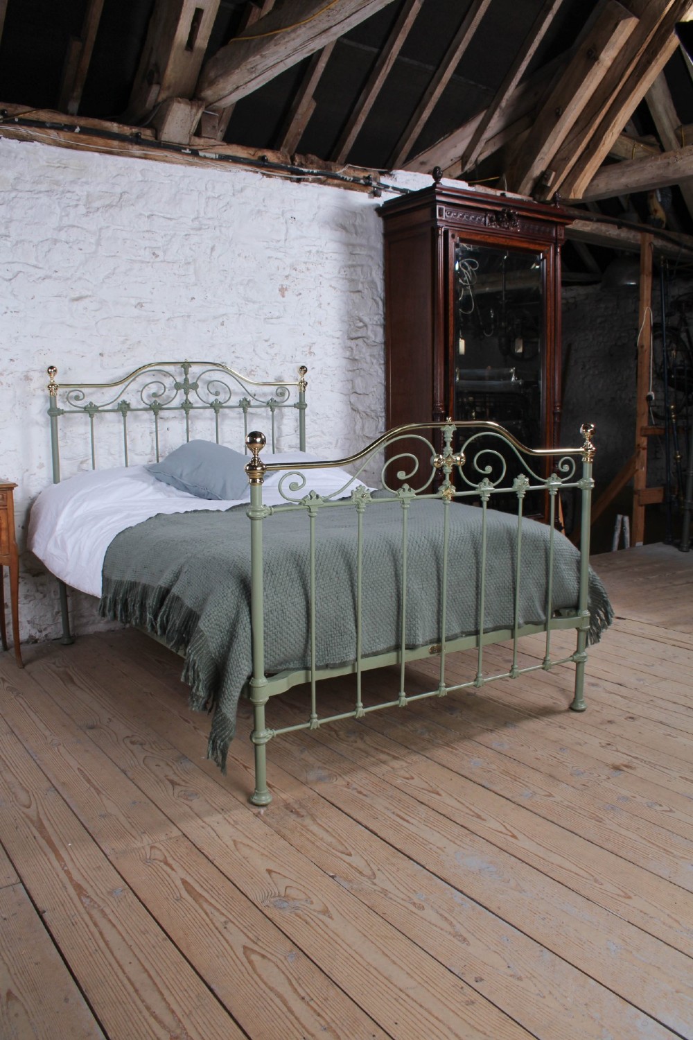 A Victorian sage green painted iron double bedstead featuring decorative scrollwork and polished brass top rails with spherical finials. View IX