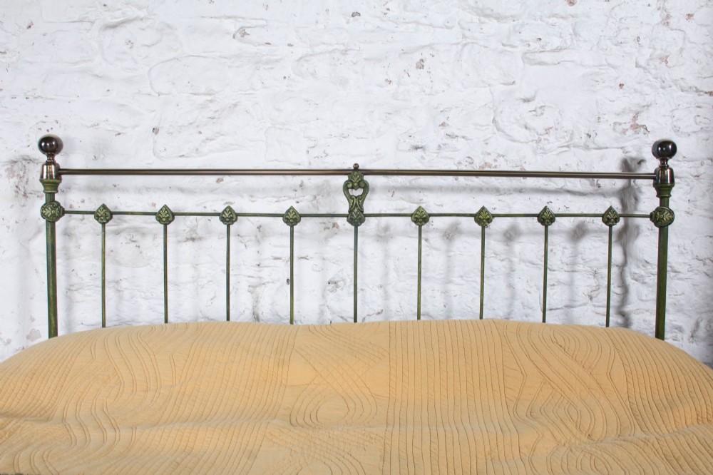 A king-size Victorian green painted iron bed frame featuring decorative central castings, vertical spindles, and a brass top rail with finials. View V