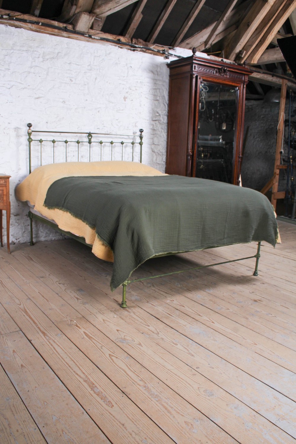 A king-size Victorian green painted iron bed frame featuring decorative central castings, vertical spindles, and a brass top rail with finials. View VII