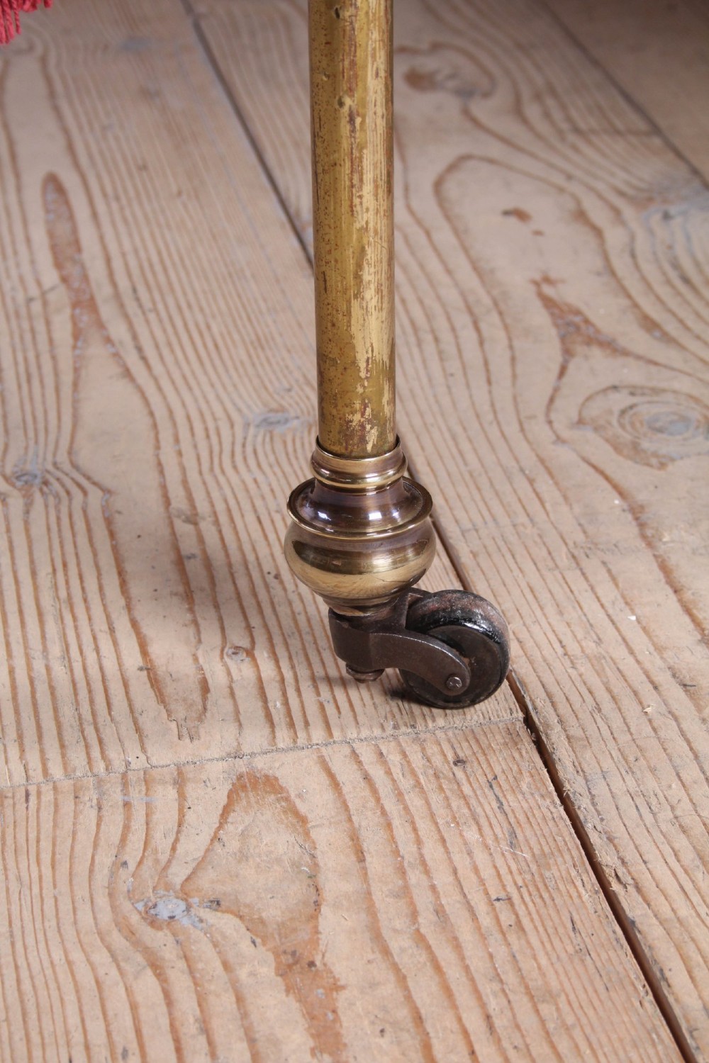 A pair of antique tubular brass single bed frames featuring rounded headboards, simple footboards, turned leg details, and brass castors. View VII