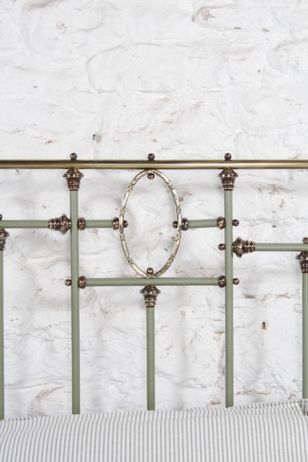 A super king French iron bedstead featuring a sage green painted frame, vertical iron spindles, brass top rails, and brass oval motifs. View V