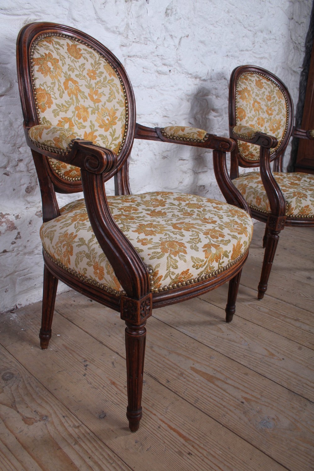 A pair of Louis XVI style carved timber armchairs with oval medallion backs and floral patterned upholstery. View V
