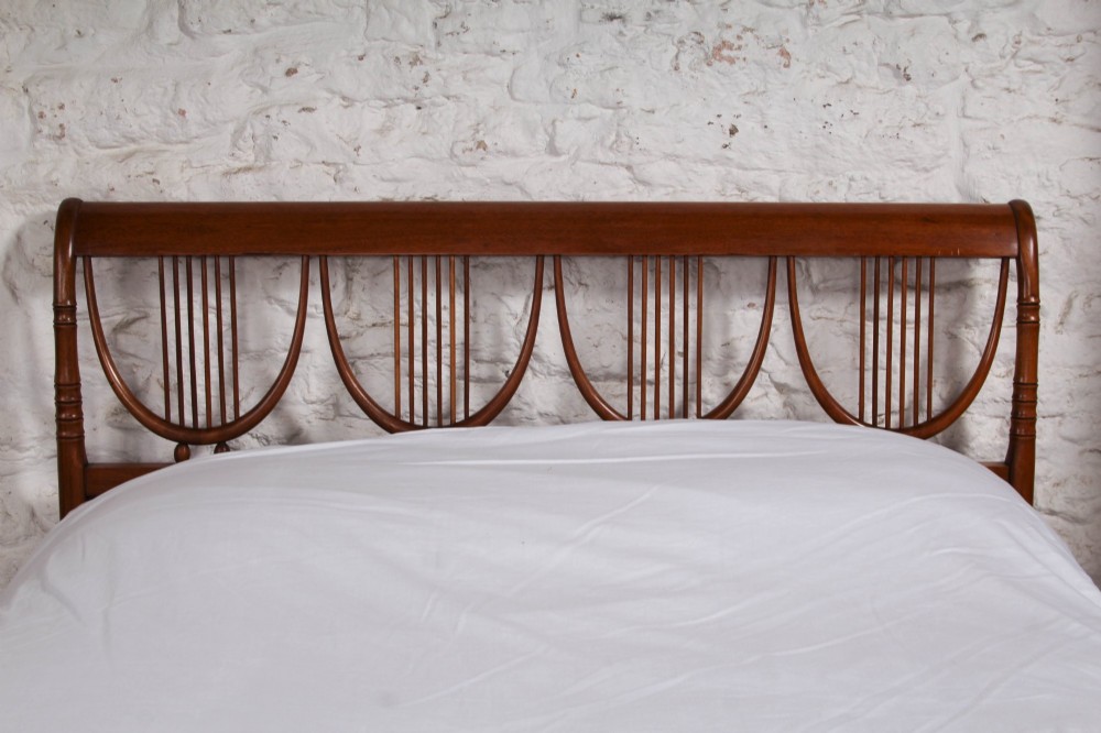 A double bed frame constructed from cherry wood featuring curved headboard and footboard panels fitted with vertical spindles. View III