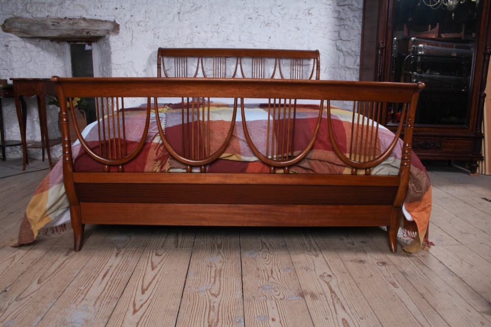 A double bed frame constructed from cherry wood featuring curved headboard and footboard panels fitted with vertical spindles. View VI