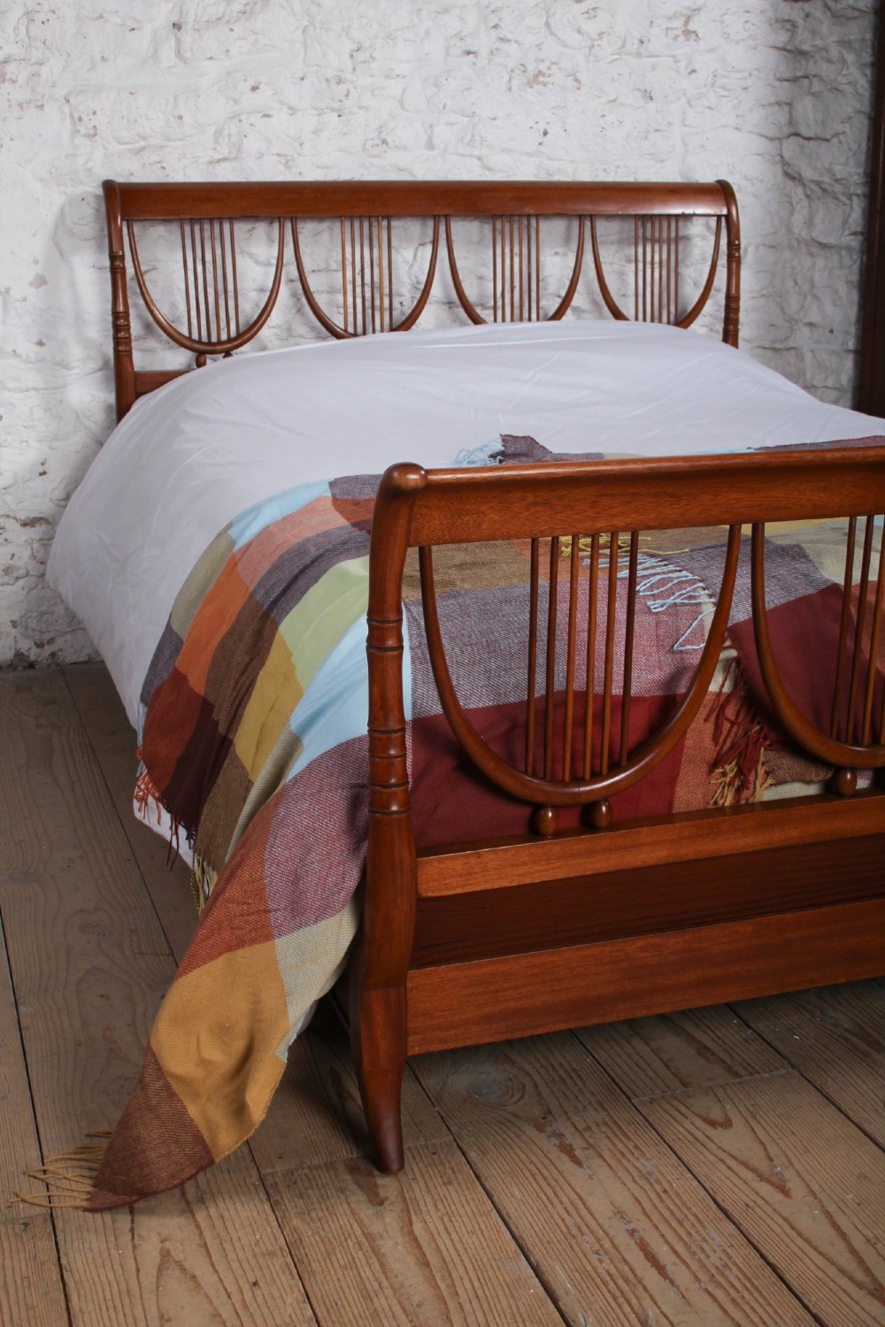 A double bed frame constructed from cherry wood featuring curved headboard and footboard panels fitted with vertical spindles. View VII