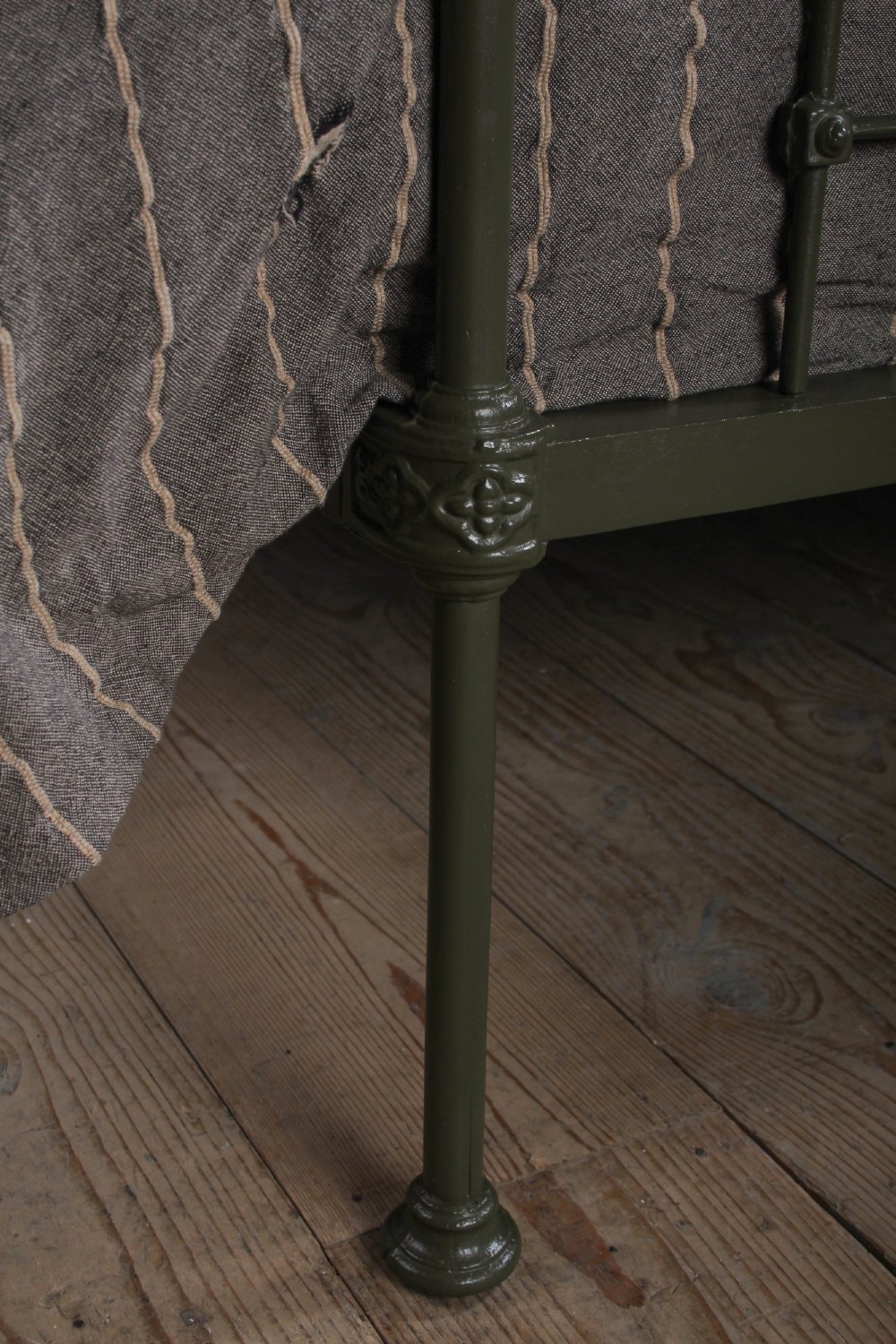 A dark green painted iron and brass king-size bedstead featuring vertical iron spindles and polished brass top rails. View V