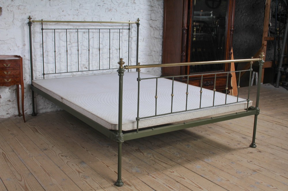 A dark green painted iron and brass king-size bedstead featuring vertical iron spindles and polished brass top rails. View X