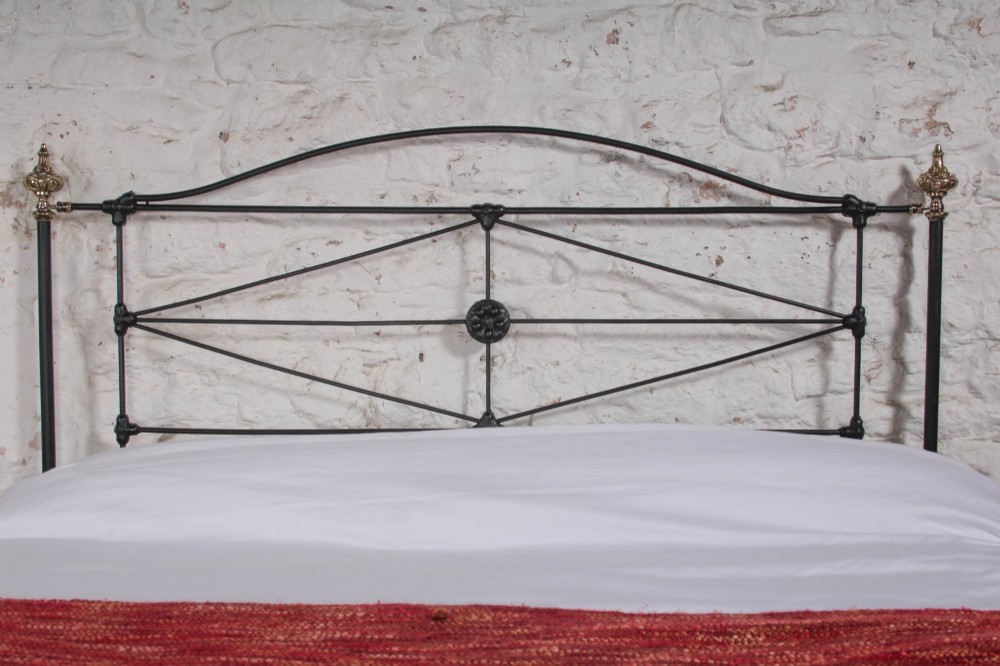 A Victorian iron and brass king-size bedstead featuring barley twist posts, ornate brass scrollwork on the footboard, and a arched black iron headboard. View VIII