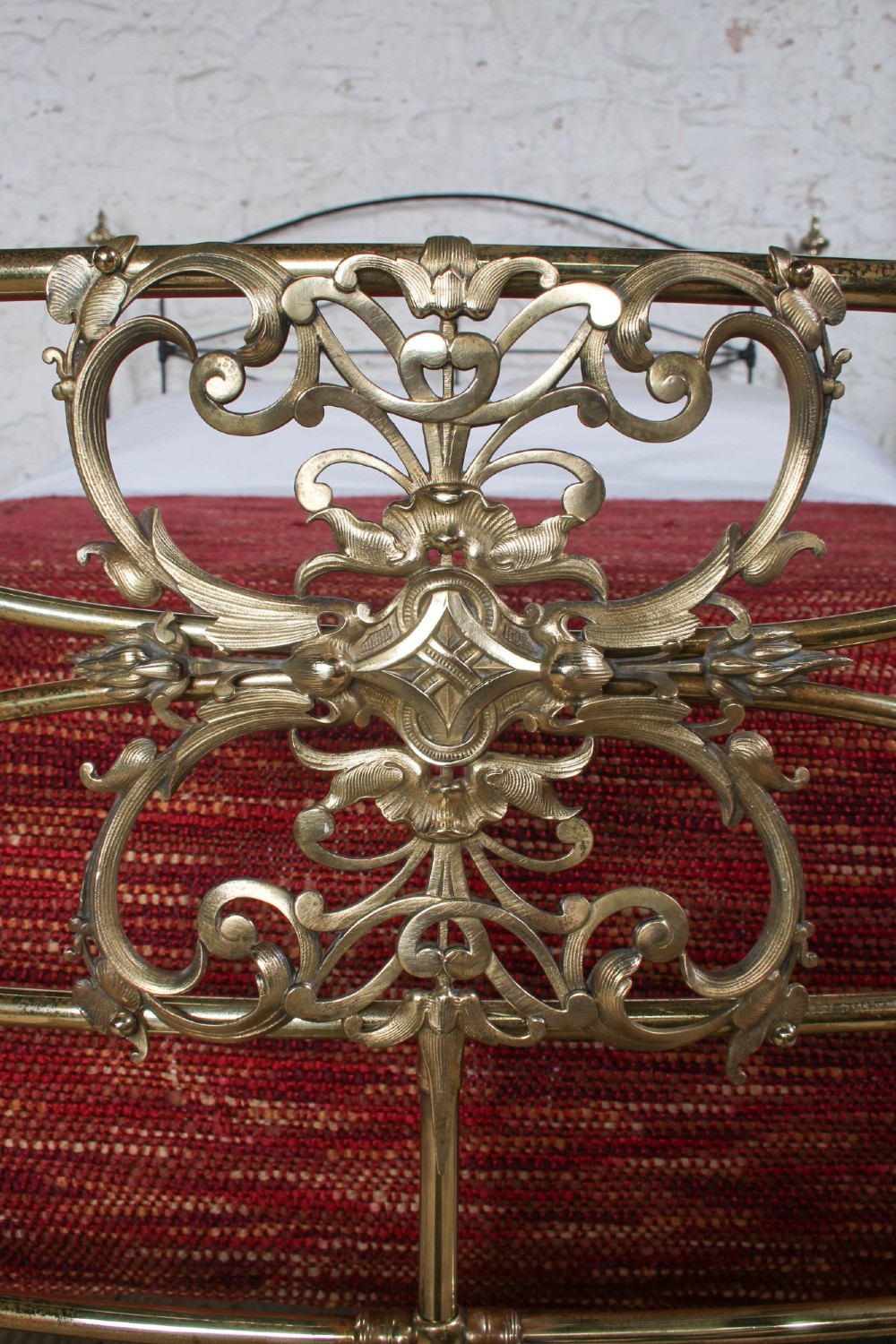 A Victorian iron and brass king-size bedstead featuring barley twist posts, ornate brass scrollwork on the footboard, and a arched black iron headboard. View X