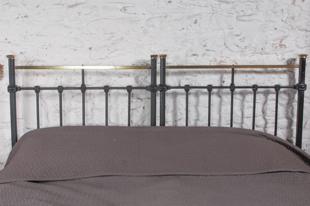 A pair of Edwardian black iron single beds featuring square tube framing, vertical spindles, and polished brass top rails. View VIII