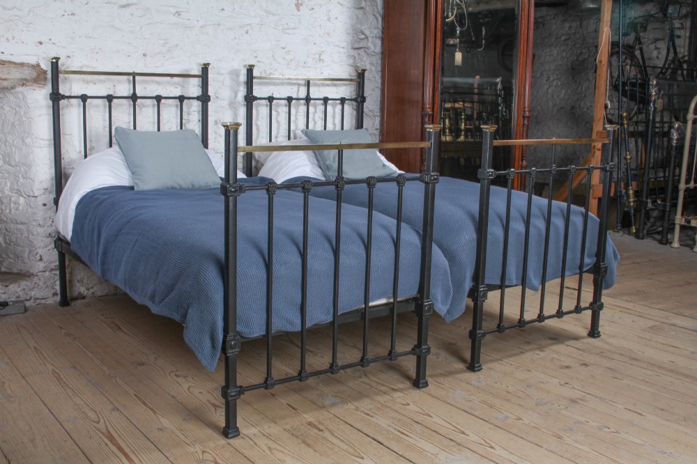 A pair of Edwardian black iron single beds featuring square tube framing, vertical spindles, and polished brass top rails. View XII