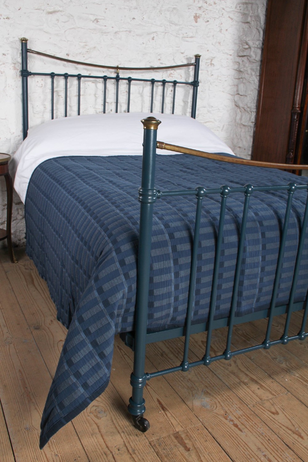 An Edwardian dark blue painted iron double bed frame featuring curved brass dip rails, vertical spindles, and ceramic castors. View IV