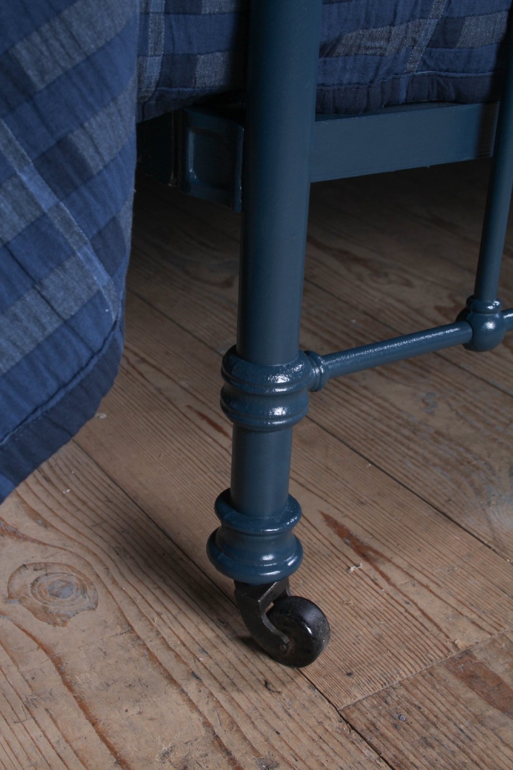 An Edwardian dark blue painted iron double bed frame featuring curved brass dip rails, vertical spindles, and ceramic castors. View V