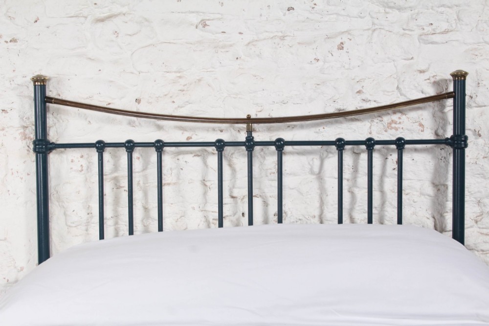 An Edwardian dark blue painted iron double bed frame featuring curved brass dip rails, vertical spindles, and ceramic castors. View VI