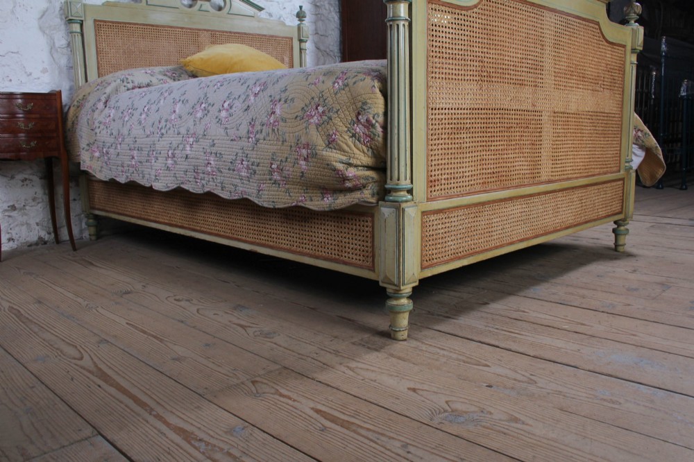 An Empire style bed frame with sage green painted timber, woven cane panels on the headboard and footboard, and carved corner finials. View II