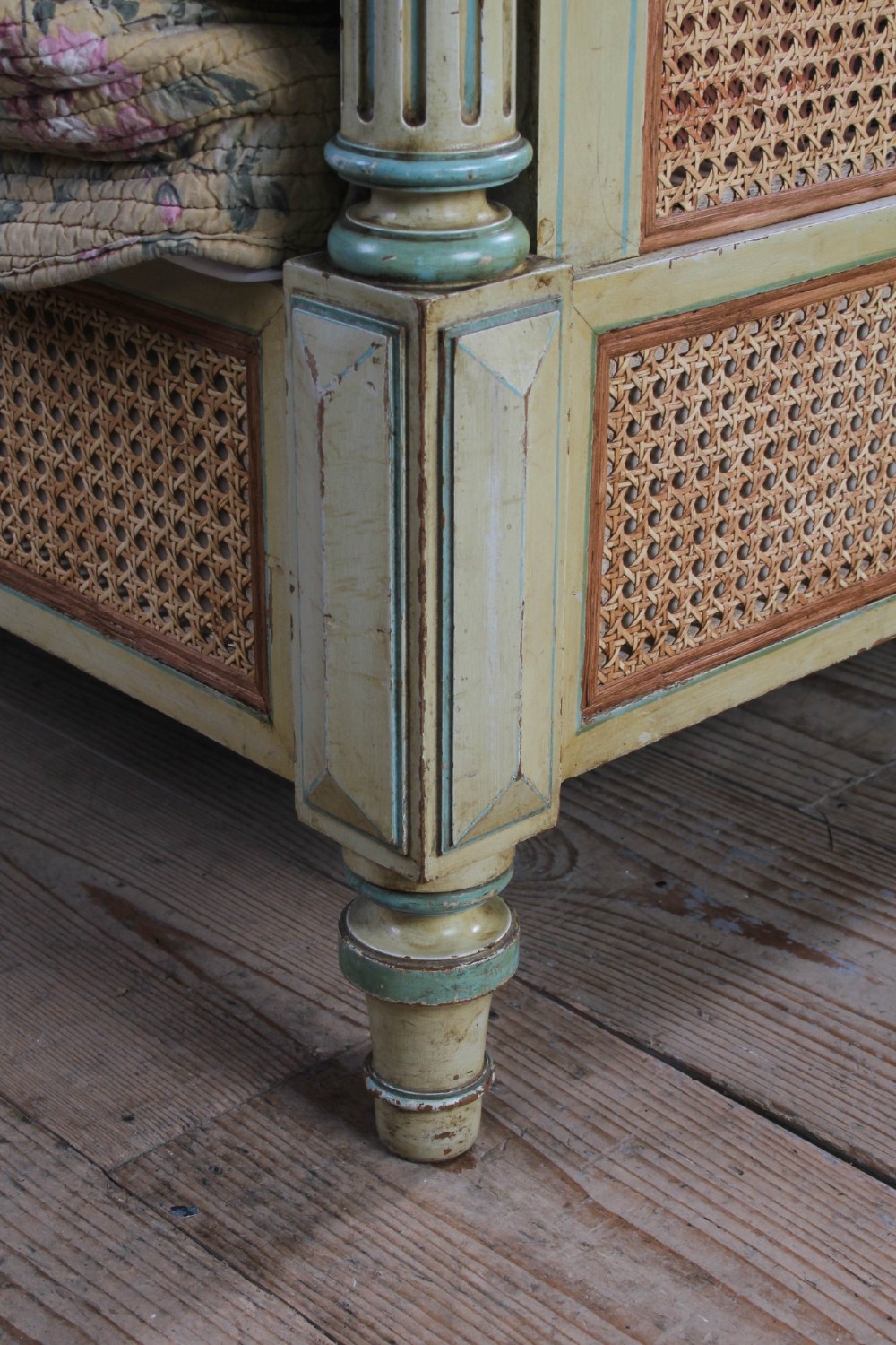 An Empire style bed frame with sage green painted timber, woven cane panels on the headboard and footboard, and carved corner finials. View VI