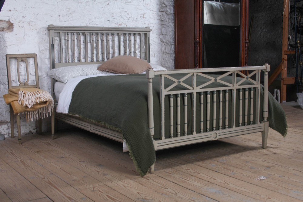 A grey painted French Arts and Crafts double bedstead featuring vertical spindle detailing and a patterned footboard.