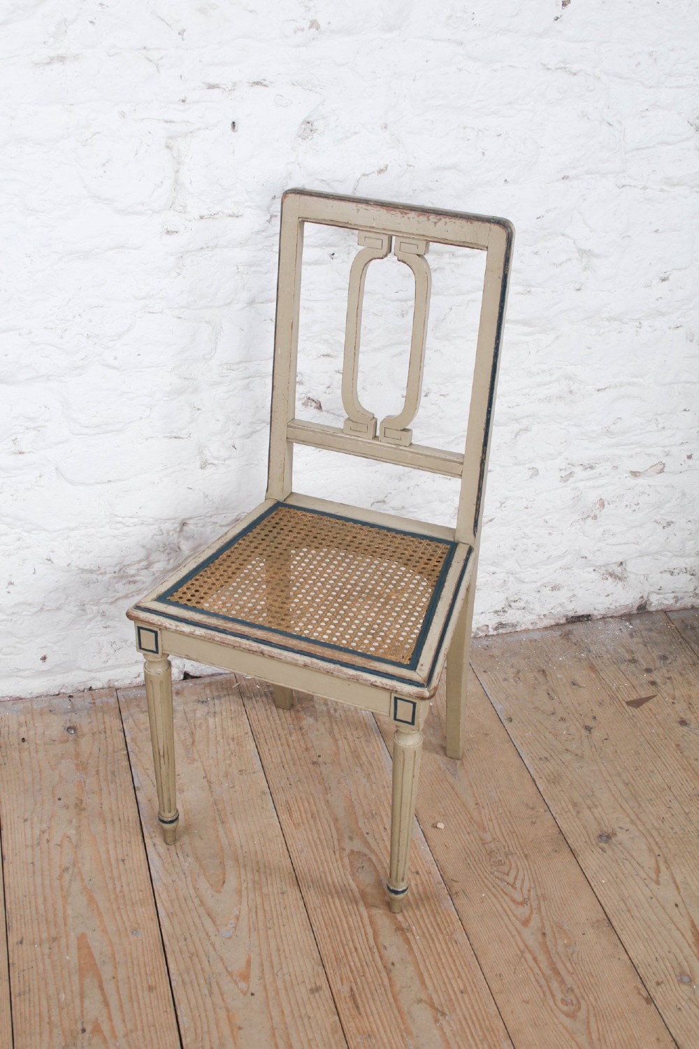 A beige painted French side chair featuring a woven cane seat, fluted tapered legs, and an open geometric back motif outlined with dark paint. View II