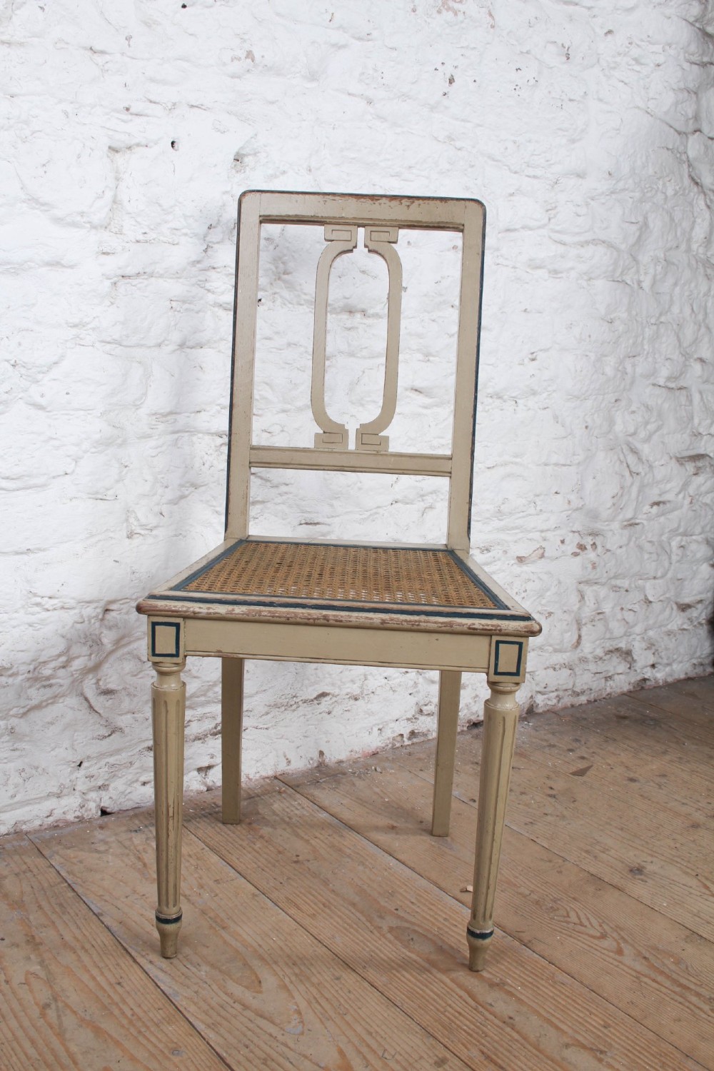 A beige painted French side chair featuring a woven cane seat, fluted tapered legs, and an open geometric back motif outlined with dark paint. View IV
