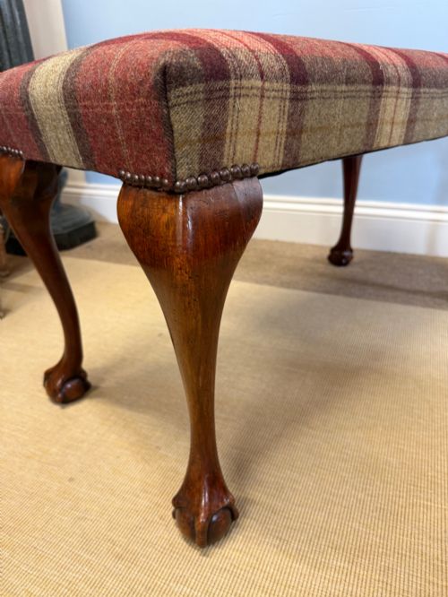 fig 1. A rectangular mahogany stool featuring tartan wool upholstery, stud trim, cabriole legs, and ball and claw feet.