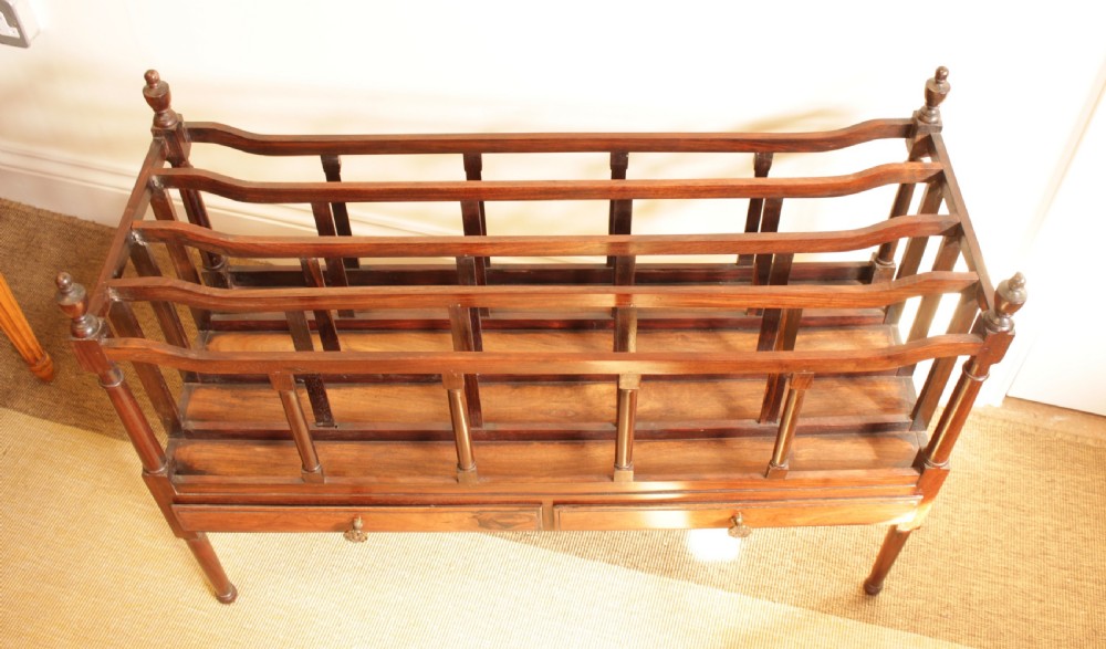 An antique Regency period dark rosewood double Canterbury featuring divided upper bays, turned corner posts with finials, two base drawers, and turned legs. View III