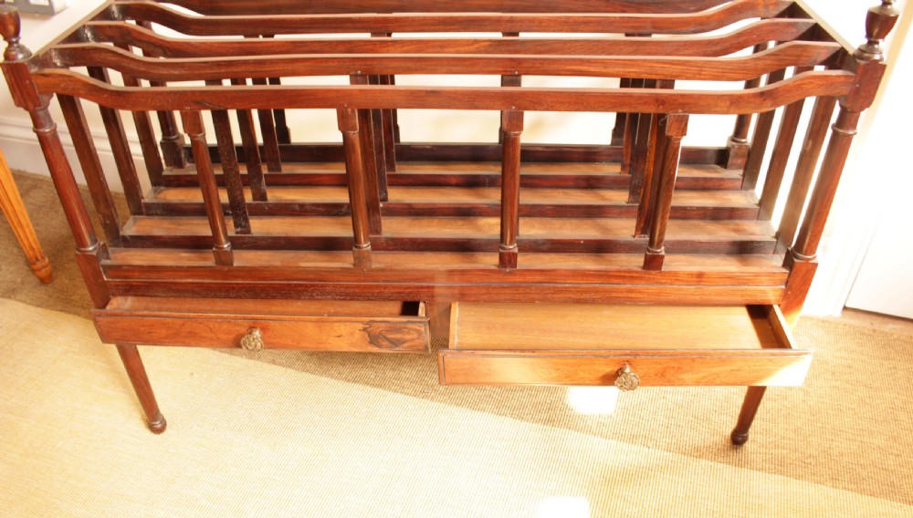 An antique Regency period dark rosewood double Canterbury featuring divided upper bays, turned corner posts with finials, two base drawers, and turned legs. View VI