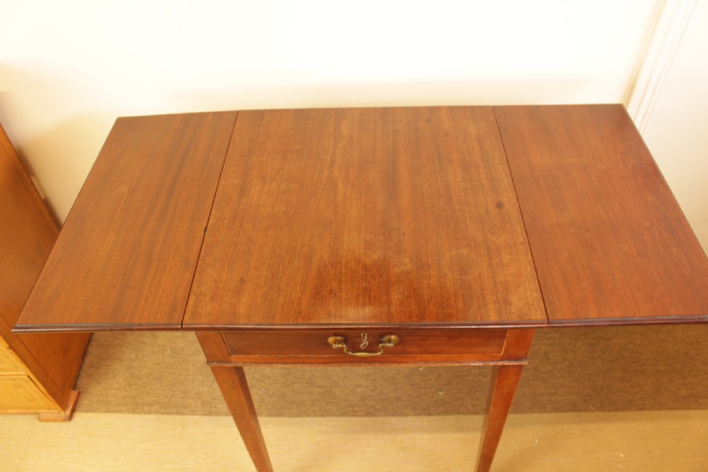 A Georgian mahogany drop-leaf side table featuring a single drawer with a brass handle, straight tapered legs, and brass castors. View II