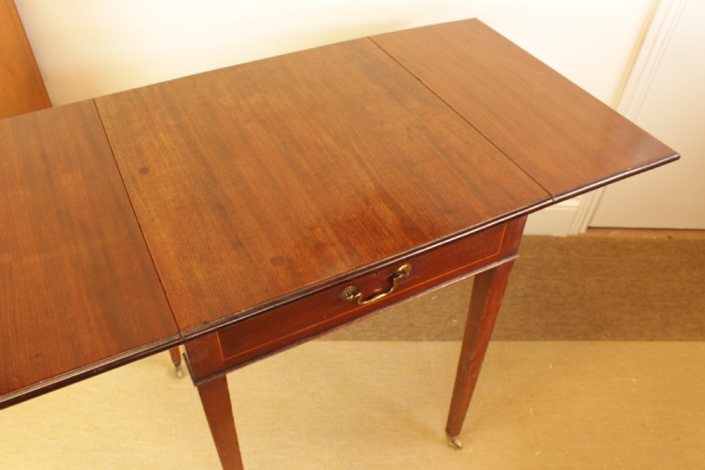 A Georgian mahogany drop-leaf side table featuring a single drawer with a brass handle, straight tapered legs, and brass castors. View VII