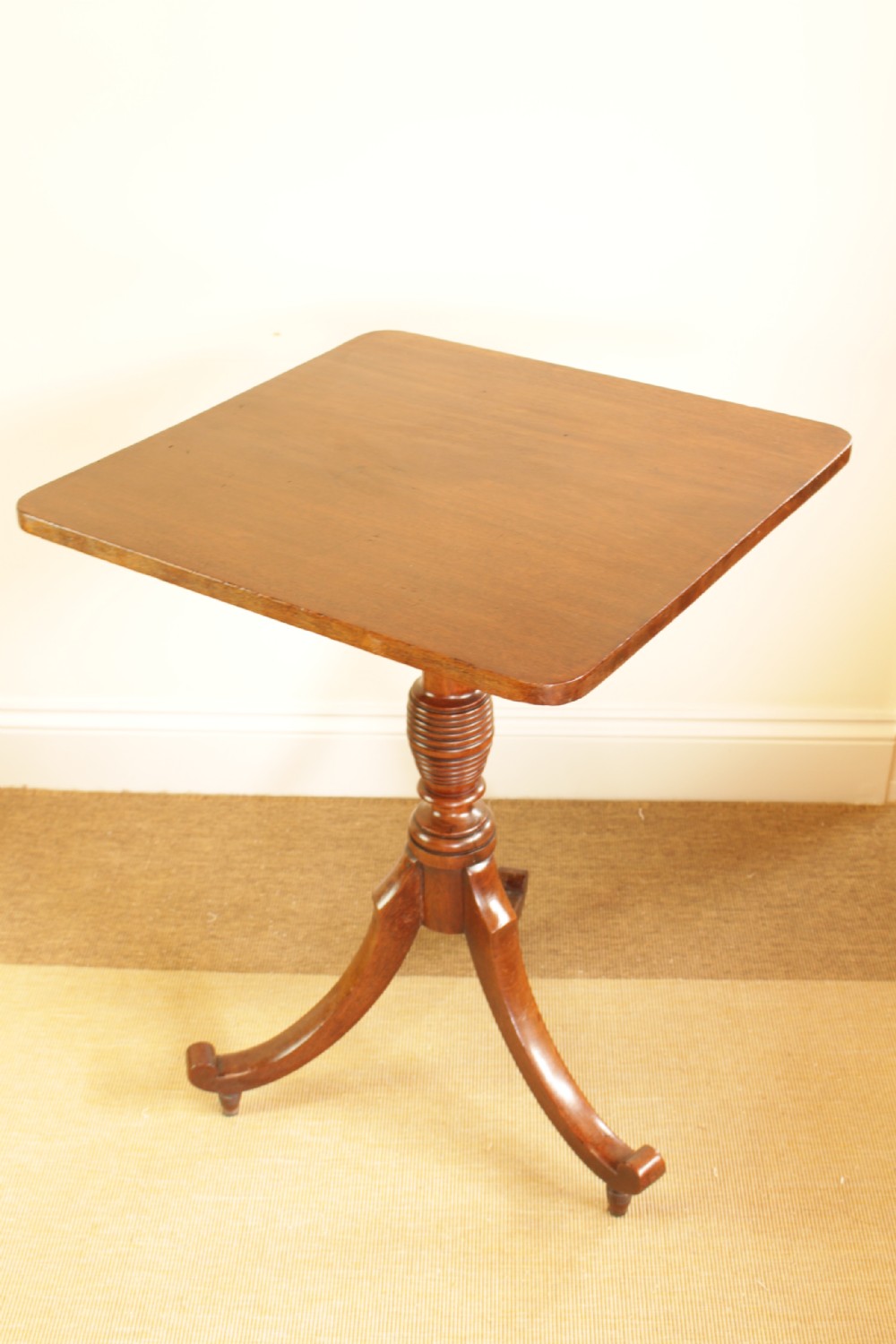A mahogany tilt-top occasional table displayed with its rectangular top locked in a vertical position above a turned central column and tripod legs. View V