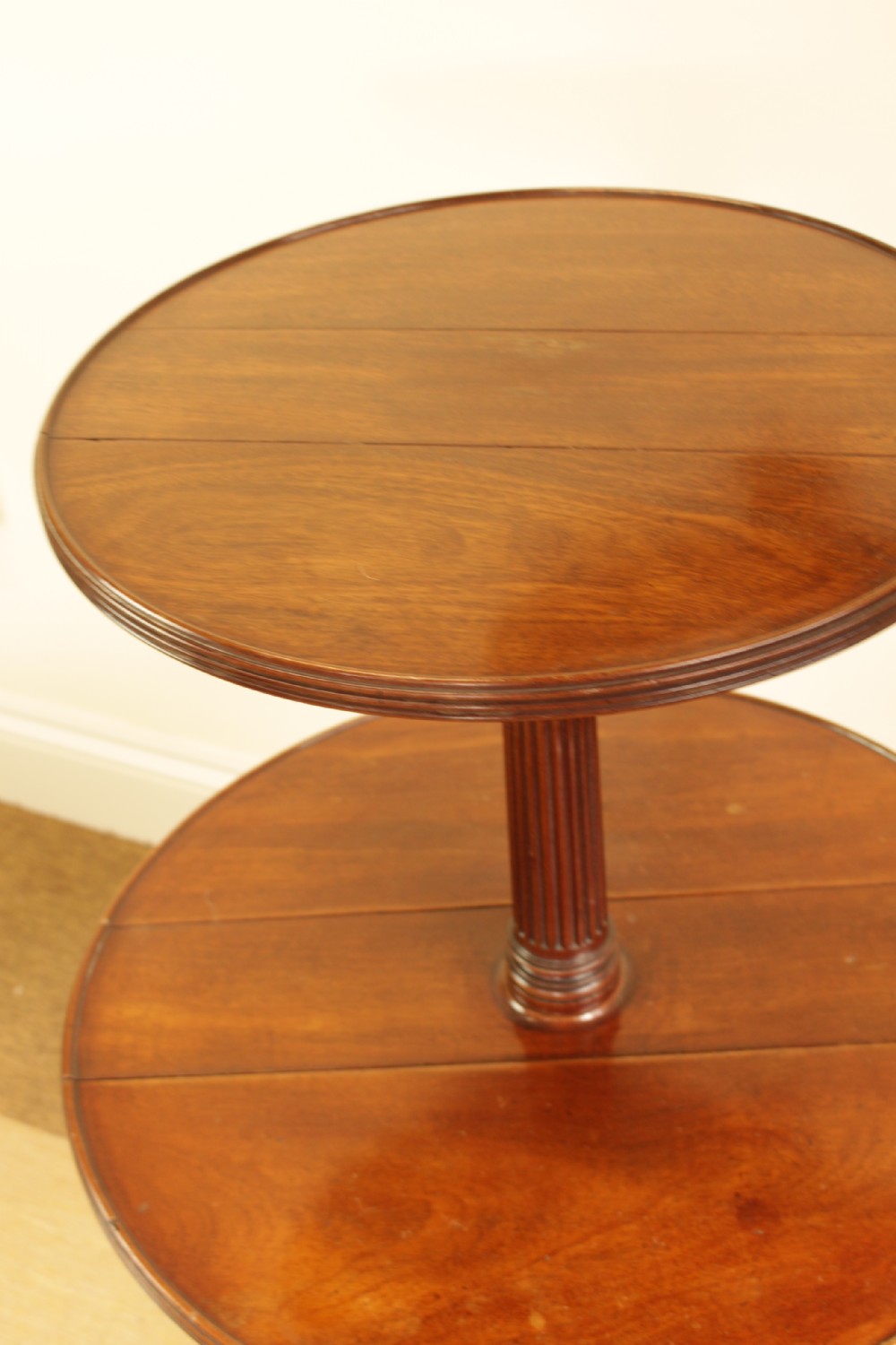 A George III mahogany two-tiered dumb waiter with folding drop-leaf sides, fluted central pillar, and tripod reeded legs on brass castors. View VII