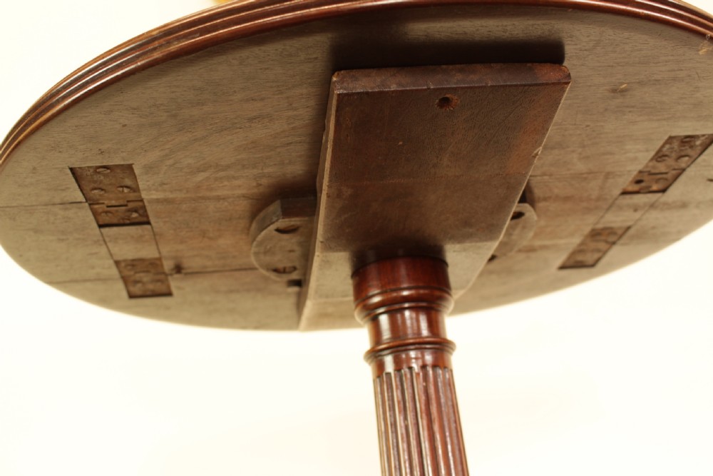 A George III mahogany two-tiered dumb waiter with folding drop-leaf sides, fluted central pillar, and tripod reeded legs on brass castors. View VIII