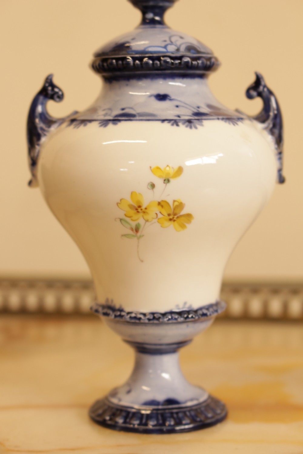 An antique porcelain lidded urn featuring hand-painted floral motifs, cobalt blue handles, and a pedestal base. View III