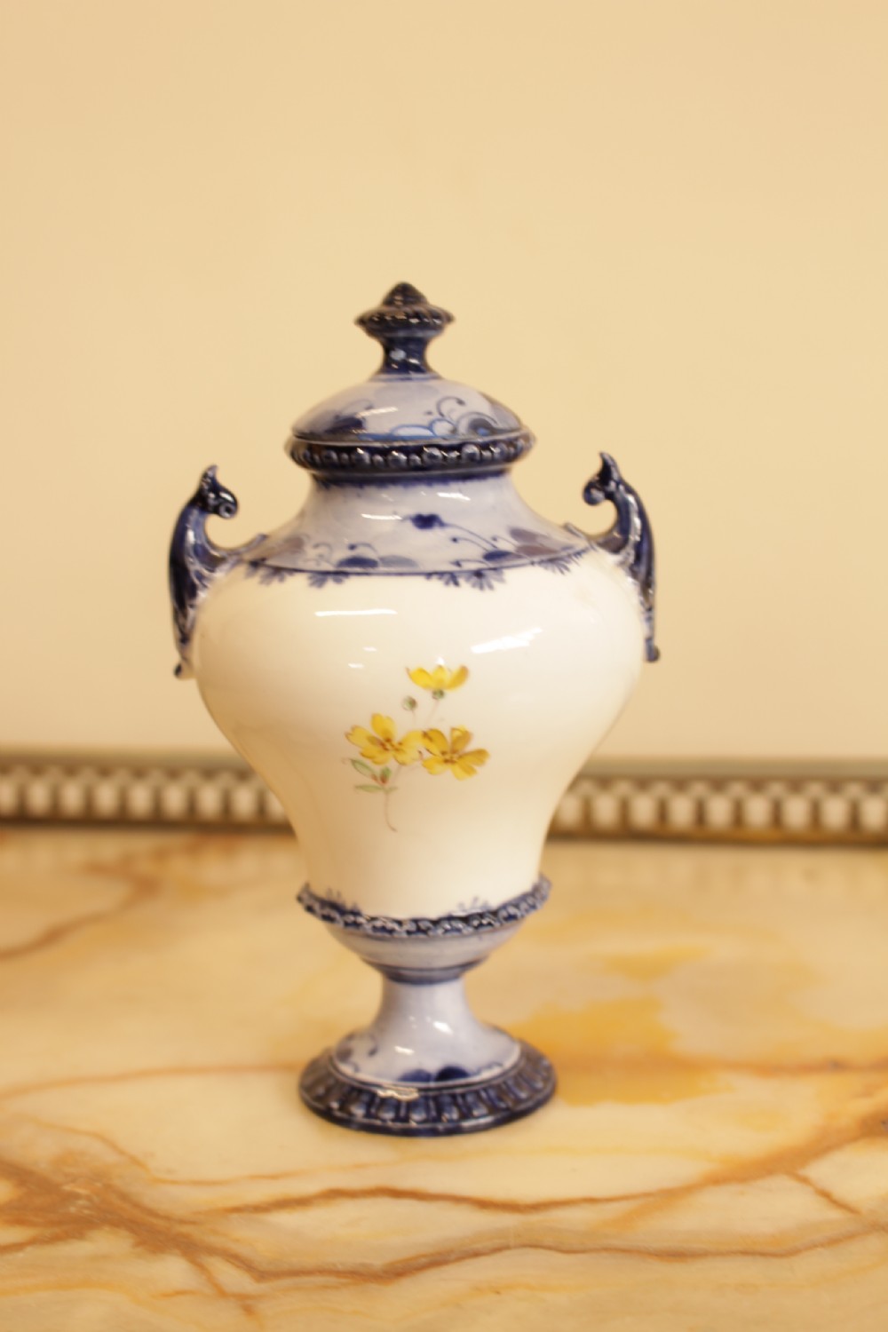 An antique porcelain lidded urn featuring hand-painted floral motifs, cobalt blue handles, and a pedestal base. View V
