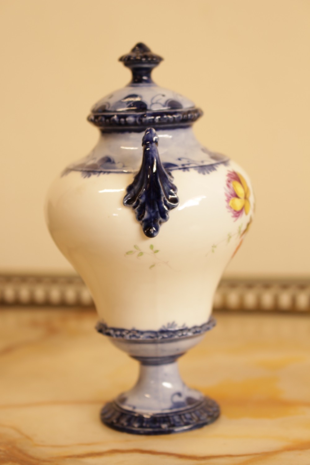 An antique porcelain lidded urn featuring hand-painted floral motifs, cobalt blue handles, and a pedestal base. View VI