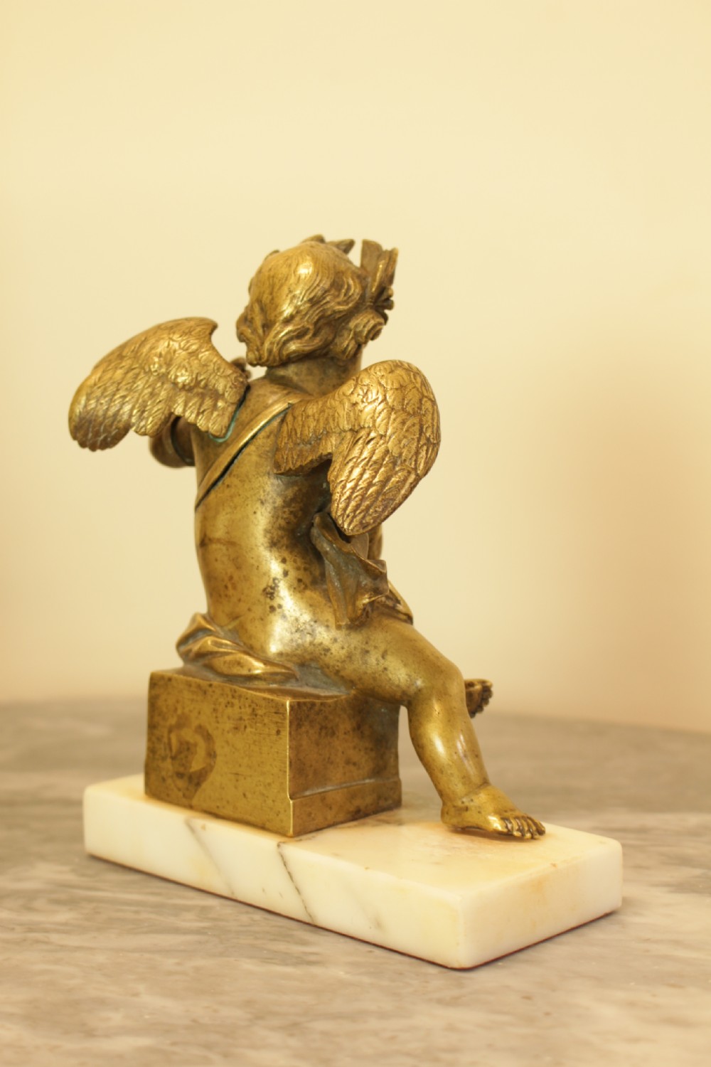 A 19th-century French gilt bronze sculpture of a winged putto wearing a laurel wreath and holding a scroll, mounted on a rectangular veined marble base. View V