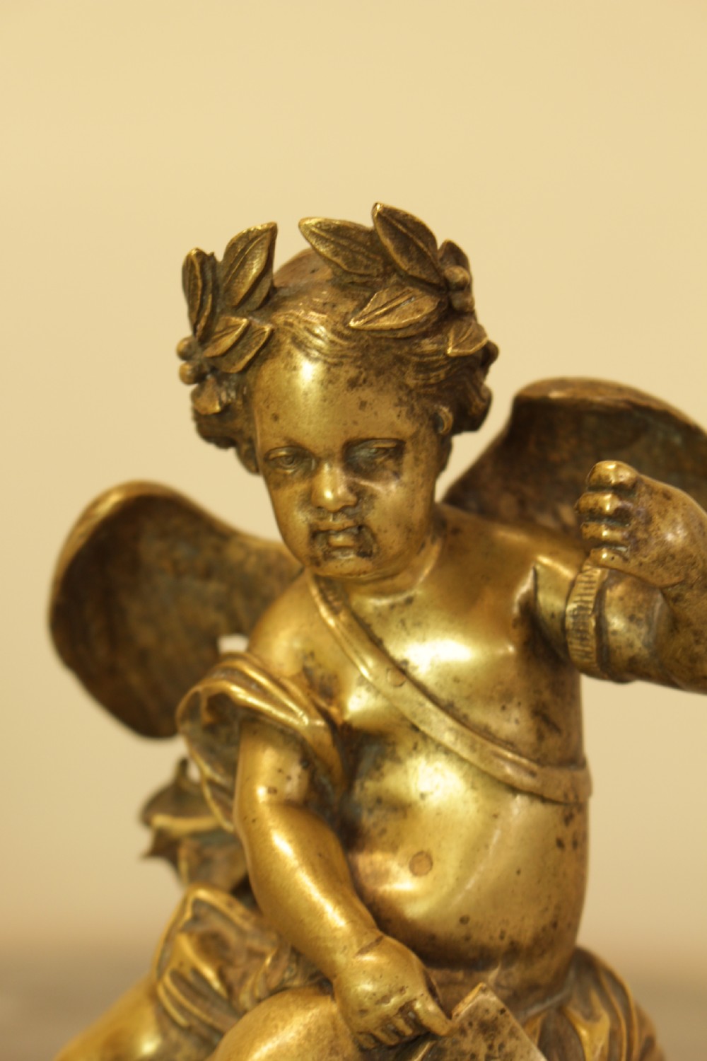 A 19th-century French gilt bronze sculpture of a winged putto wearing a laurel wreath and holding a scroll, mounted on a rectangular veined marble base. View VII