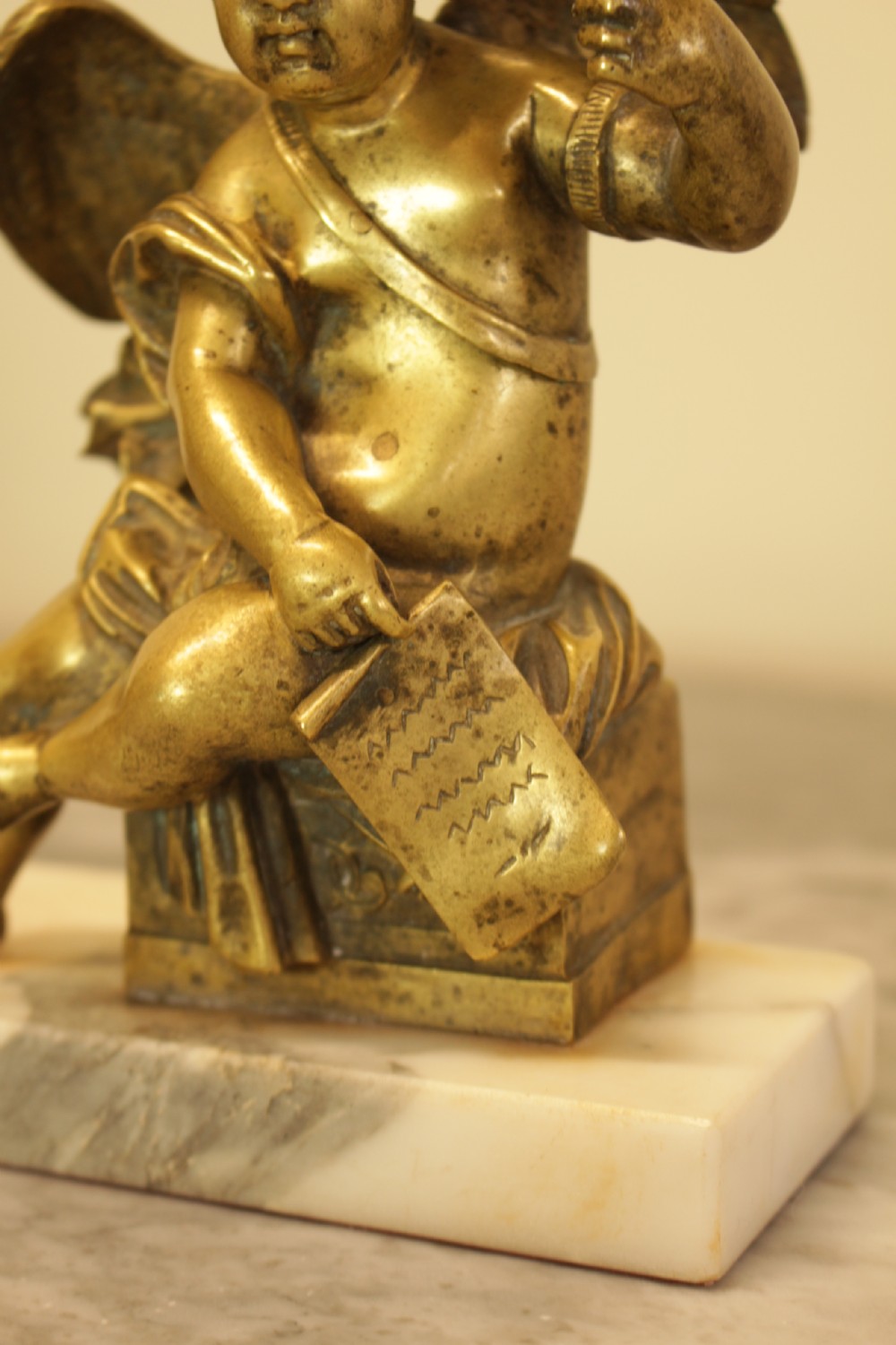 A 19th-century French gilt bronze sculpture of a winged putto wearing a laurel wreath and holding a scroll, mounted on a rectangular veined marble base. View VIII