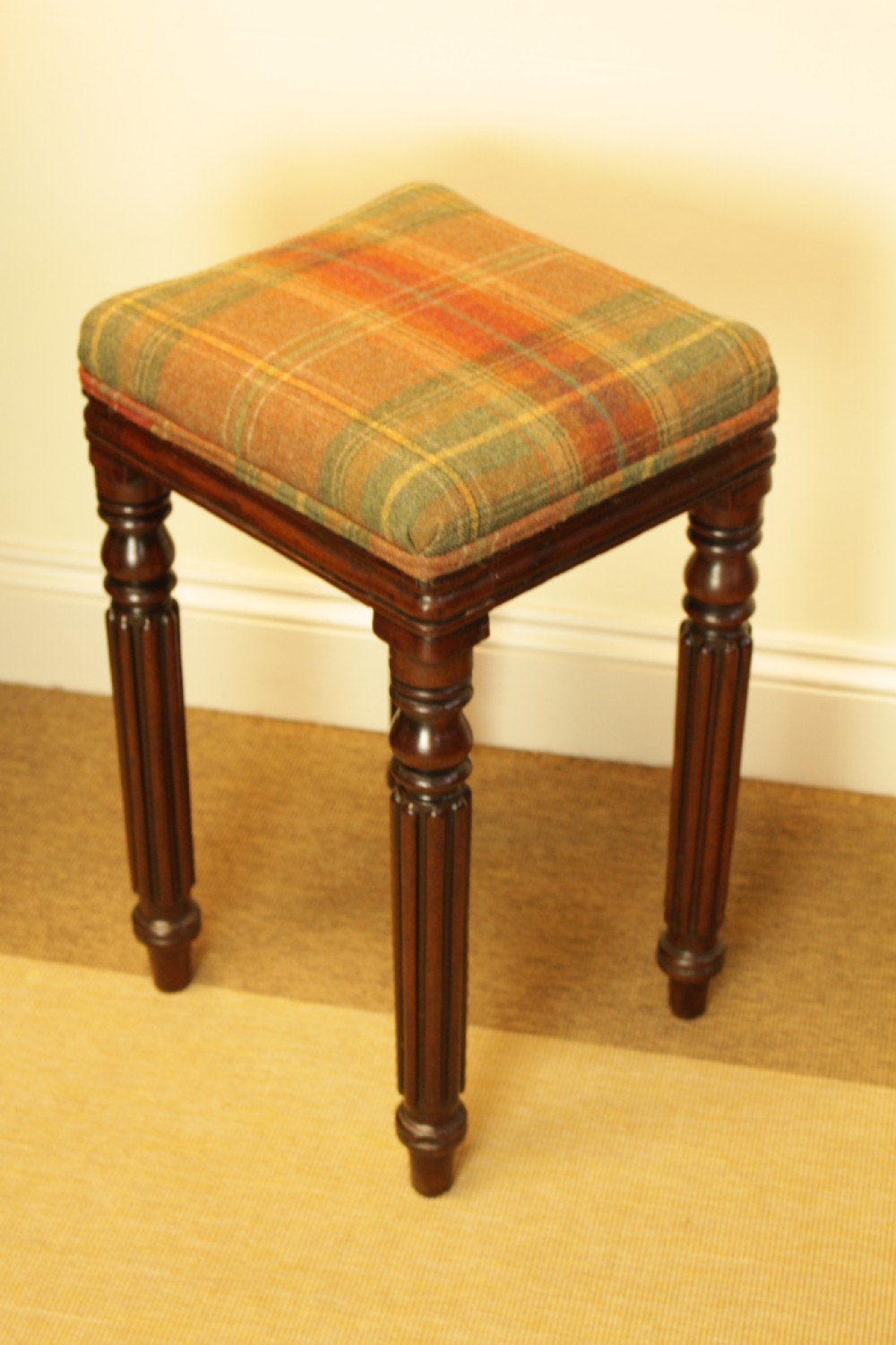 A 19th-century mahogany stool featuring turned reeded legs and a square tartan wool upholstered seat.