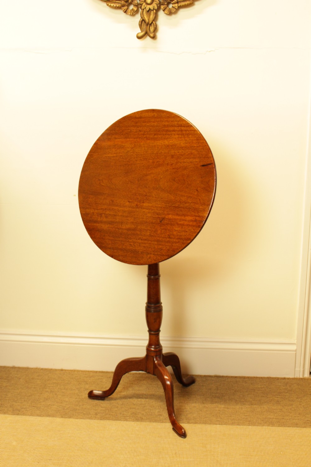 A George III period circular mahogany tilt-top table with a turned central column and tripod cabriole legs.