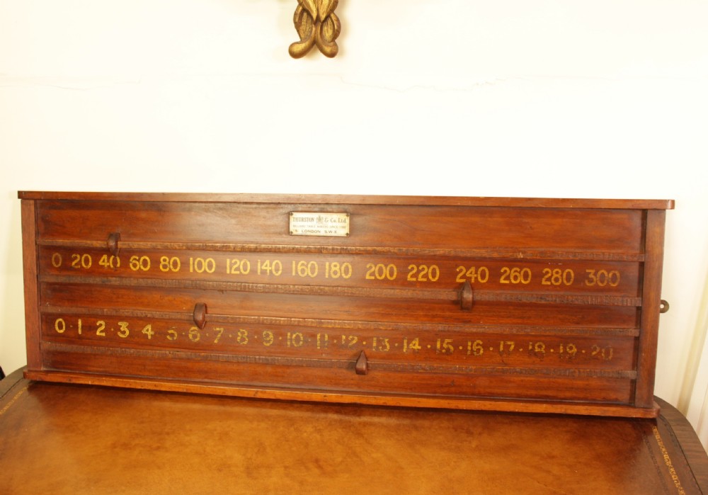 A rectangular mahogany billiards scoring board featuring two horizontal tracks with sliding wooden markers, yellow painted numbers, and a maker plaque at the top centre. View II