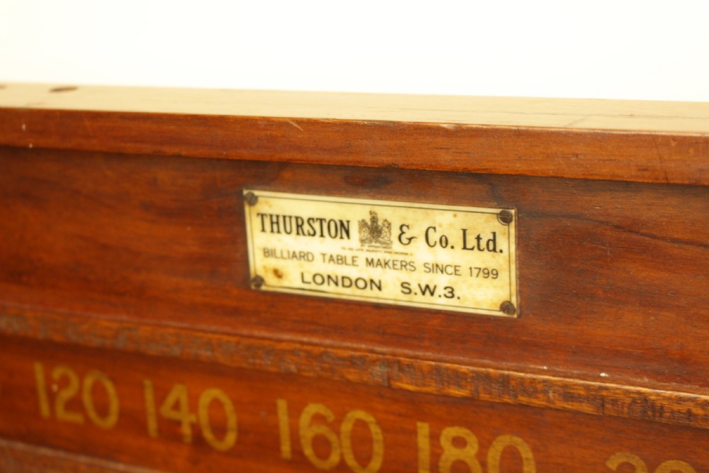 A rectangular mahogany billiards scoring board featuring two horizontal tracks with sliding wooden markers, yellow painted numbers, and a maker plaque at the top centre. View VI